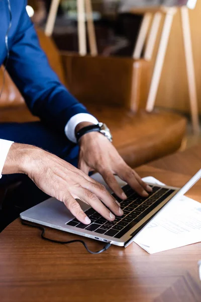 Cropped view of businessman in suit using laptop in hotel — Stock Photo