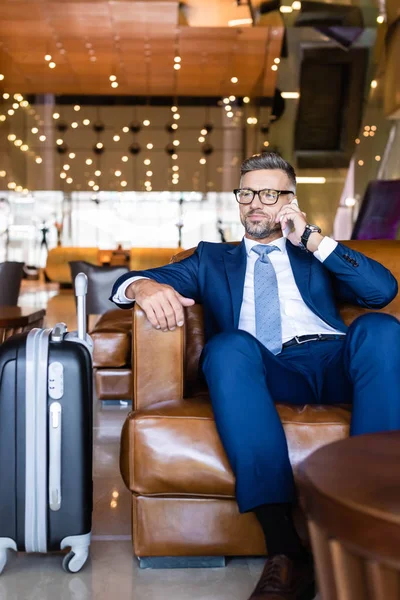 Hombre de negocios guapo en traje y gafas hablando en smartphone - foto de stock