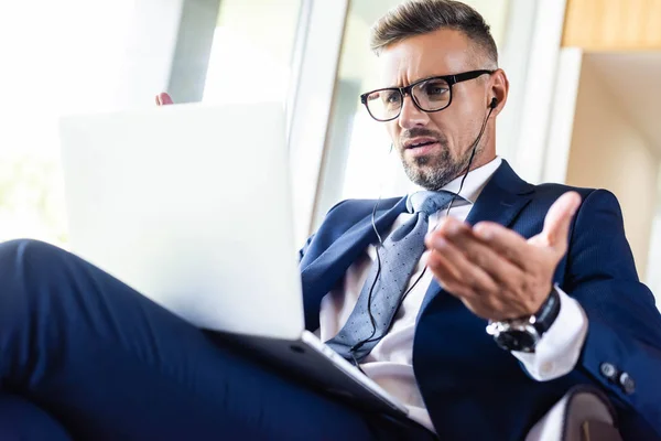 Low angle view of handsome businessman in suit and glasses using laptop — Stock Photo