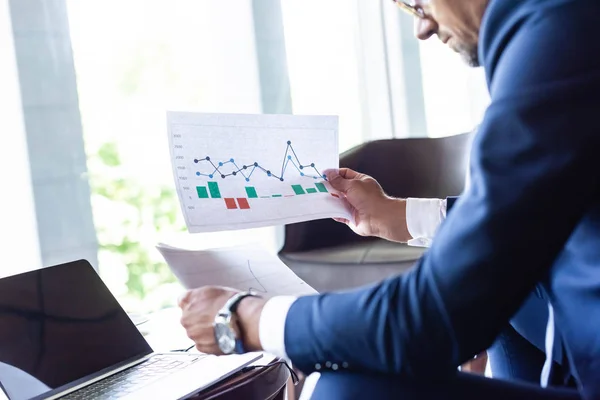 Vue recadrée de l'homme en tenue de cérémonie en regardant des papiers avec des graphiques et des graphiques — Photo de stock