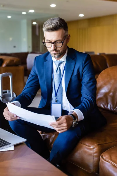 Bel homme d'affaires en costume et lunettes regardant les papiers — Photo de stock