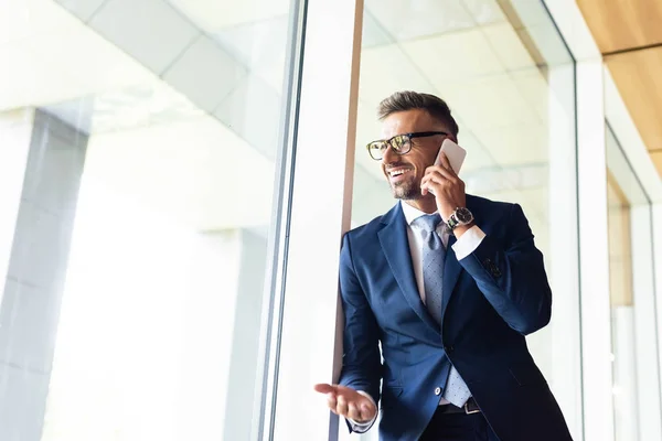 Handsome businessman in suit and glasses talking on smartphone — Stock Photo