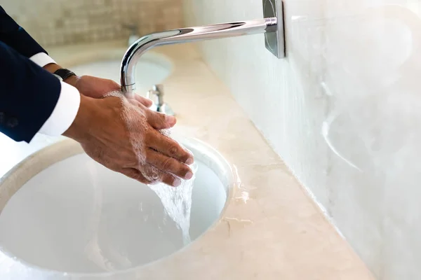 Обрезанный вид человека, моющего руки в общественном туалете — стоковое фото