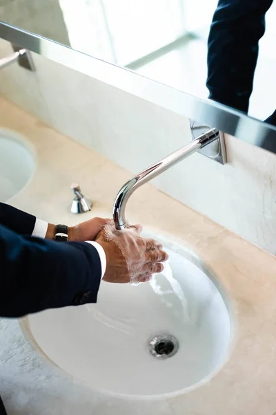 High angle view of man washing hands in public bathroom — Stock Photo