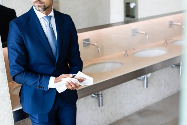 Cropped view of businessman in formal wear wiping hands — Stock Photo