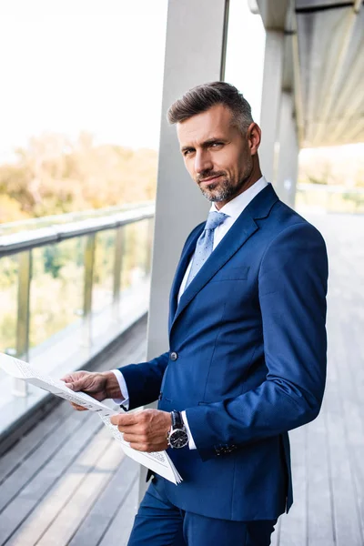 Handsome and confident businessman in formal wear holding newspaper — Stock Photo