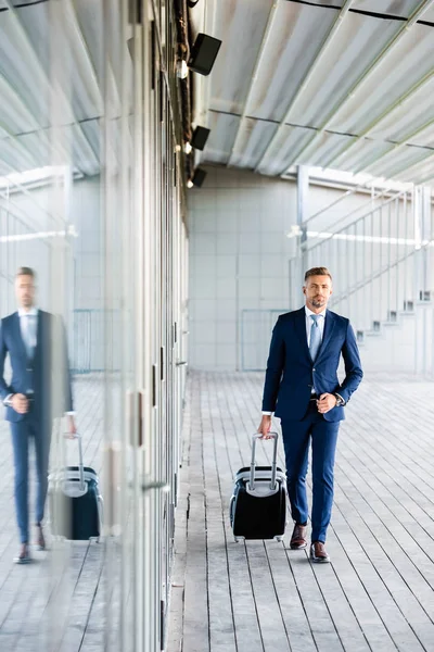 Handsome and confident businessman in formal wear holding suitcase — Stock Photo