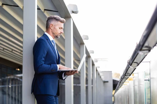 Vue latérale de bel homme d'affaires en tenue formelle à l'aide d'un ordinateur portable — Photo de stock