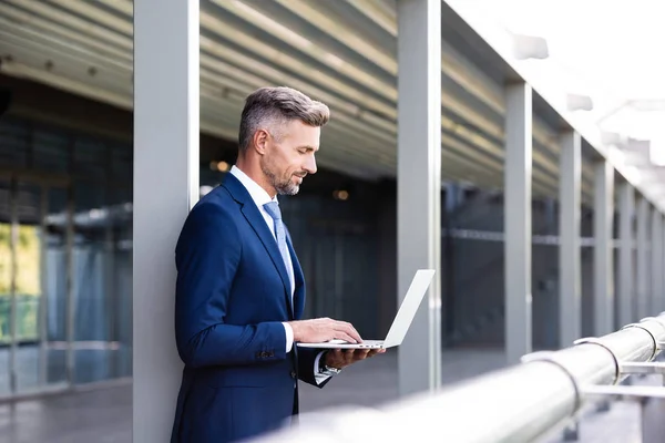 Side view of handsome businessman in formal wear using laptop — Stock Photo