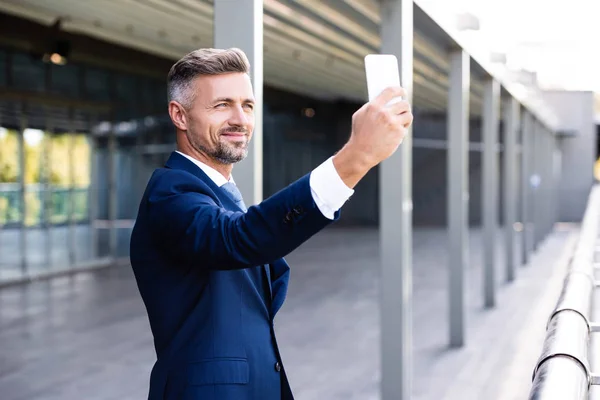 Handsome and confident businessman in formal wear talking selfie — Stock Photo