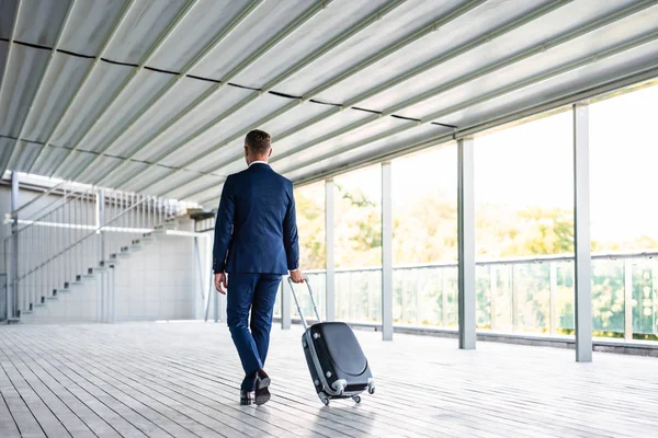 Vista posterior del hombre de negocios en la maleta de sujeción de desgaste formal - foto de stock