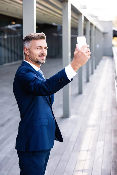 Gutaussehender und selbstbewusster Geschäftsmann in formeller Kleidung, der ein Selfie macht — Stockfoto