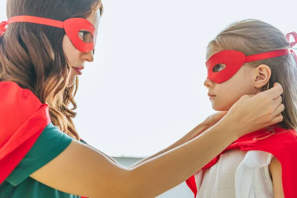 Side view of woman and adorable daughter in costumes of superheroes looking at each other — Stock Photo