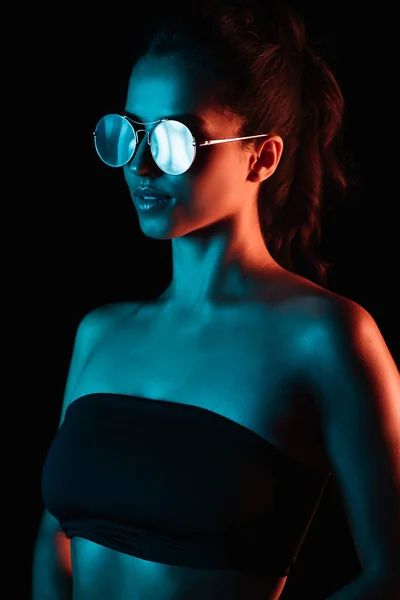 Élégant jeune femme dans des lunettes de soleil isolé sur noir — Photo de stock