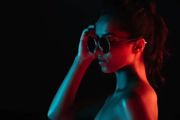 Atractiva joven en gafas de sol aisladas en negro - foto de stock