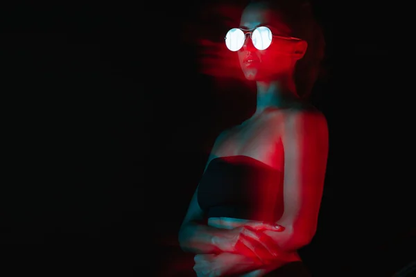 Flou de mouvement de la femme attrayante dans les lunettes de soleil sur noir — Photo de stock