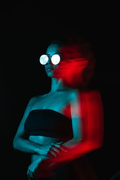 Flou de mouvement de jeune femme attrayante dans des lunettes de soleil sur noir — Photo de stock