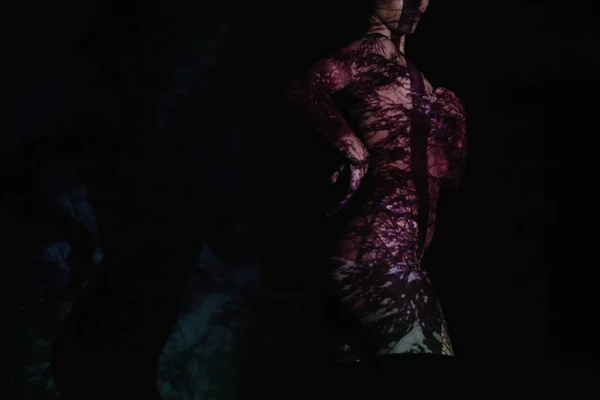 Recortado vista de chica desnuda con sombras en el cuerpo de pie en negro - foto de stock