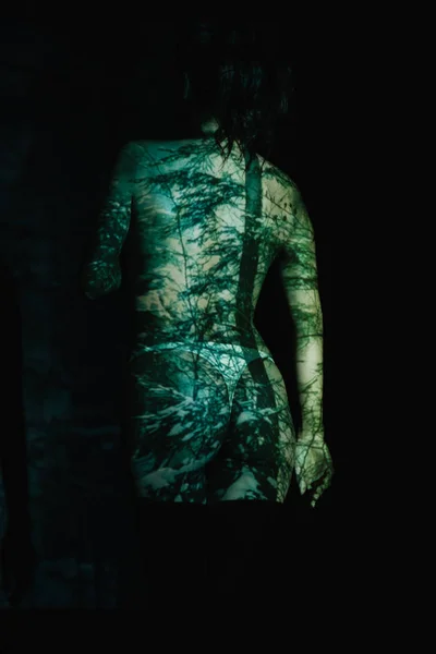 Rückansicht eines unbekleideten Mädchens mit Schatten auf dem Körper, das auf schwarz steht — Stockfoto