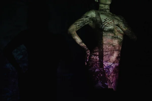 Vista ritagliata di svestita giovane donna con ombre sul corpo mentre in piedi sul nero — Foto stock