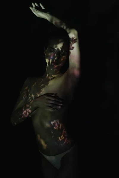 Роздягнена дівчина з закритими очима і тінями на тілі, що стоїть ізольовано на чорному — стокове фото