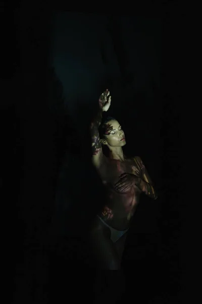 Unbekleidetes Mädchen mit geschlossenen Augen und Schatten auf dem Körper, der auf schwarz steht — Stockfoto