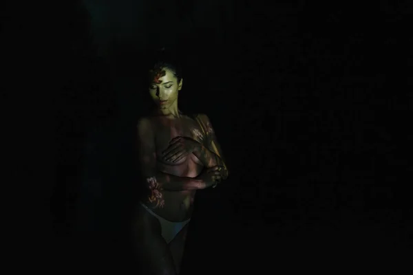 Роздягнена жінка з закритими очима і тінями на тілі, стоячи на чорному — стокове фото