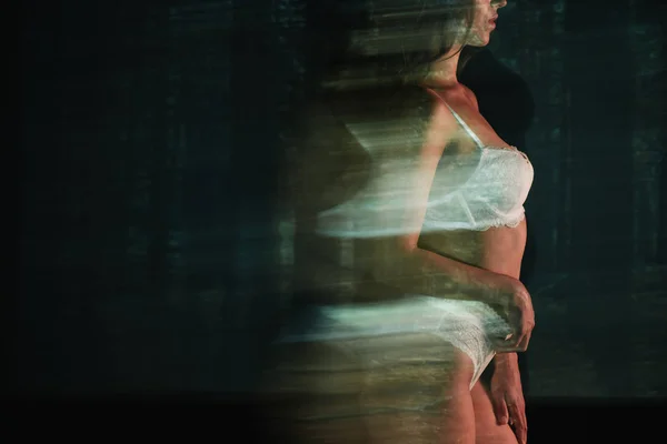 Desenfoque movimiento de chica en ropa interior blanca de encaje cerca de los árboles - foto de stock