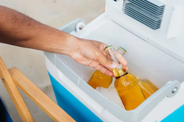 Cropped view of young man taking bottles of beer from portable fridge — Stock Photo