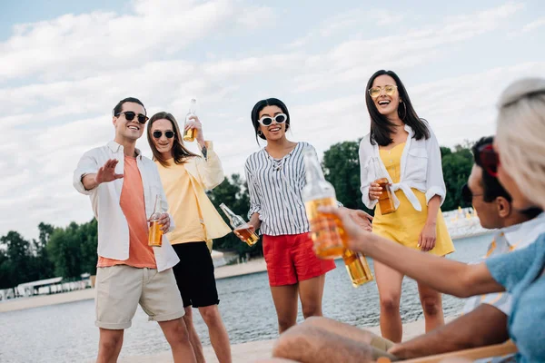 Alegre, jóvenes amigos multiculturales divertirse y beber cerveza en la playa - foto de stock