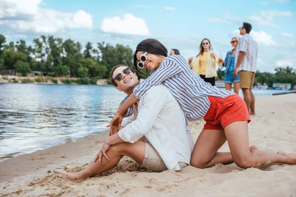 Jeune couple interracial s'amuser sur la plage près d'amis multiculturels — Photo de stock