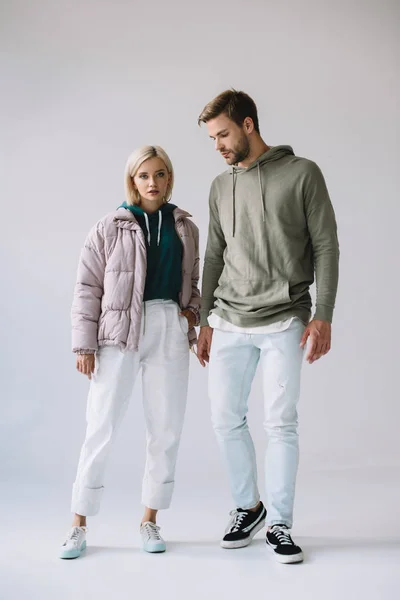 Vista completa de la chica rubia con estilo y el hombre barbudo en gris - foto de stock