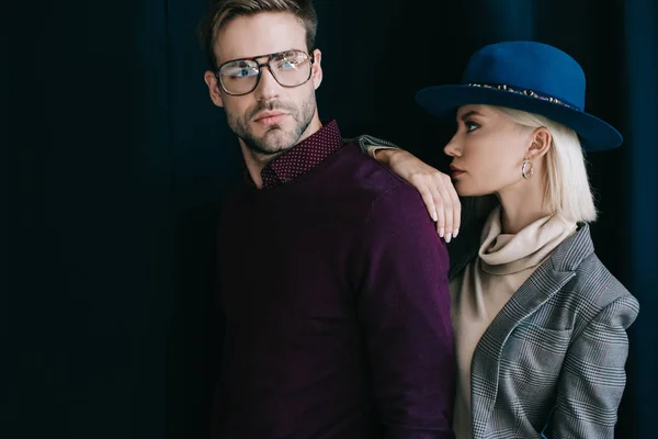 Stylish young man in glasses and blonde woman in hat near curtain — Stock Photo