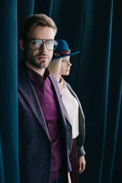 Jovem elegante em óculos e mulher loira em chapéu perto de cortina — Fotografia de Stock