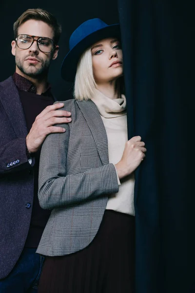 Elegante junge Frau mit Hut und Mann mit Brille in der Nähe des Vorhangs — Stockfoto