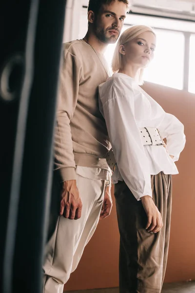 Stilvolles Paar steht neben Vorhang und blickt in die Kamera — Stockfoto