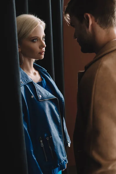 Elegante mujer joven y hombre en trajes de otoño mirándose entre sí - foto de stock