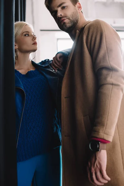 Stylish young woman and man in autumn clothes near black curtain — Stock Photo