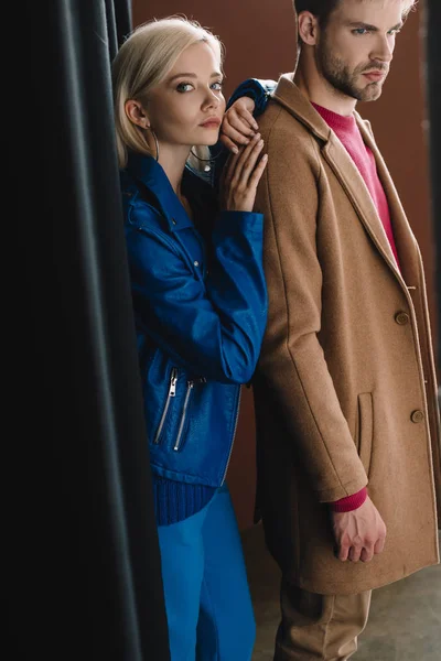 Mujer joven y elegante hombre en ropa de otoño cerca de la cortina negra - foto de stock