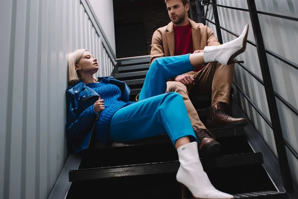 Стильна молода жінка і чоловік в осінньому одязі, сидячи на сходах — стокове фото