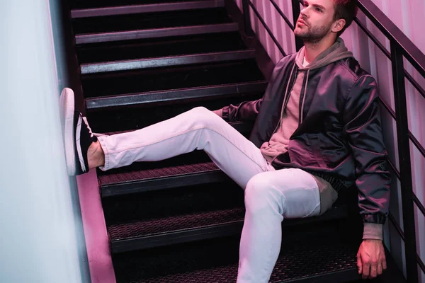 Nachdenklicher bärtiger junger Mann in Jacke sitzt auf der Treppe — Stockfoto