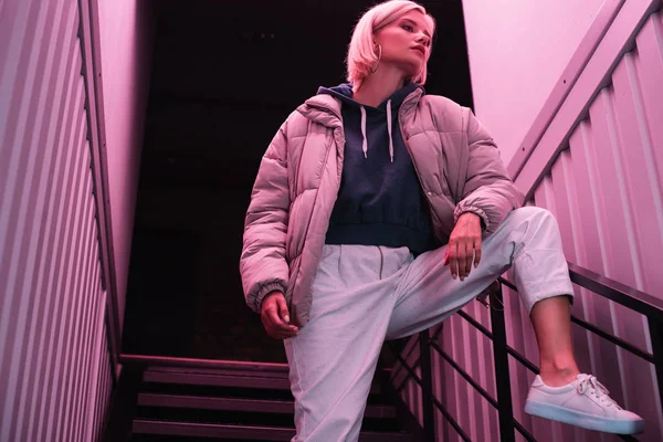 Blonde young woman in down jacket on stairs — Stock Photo