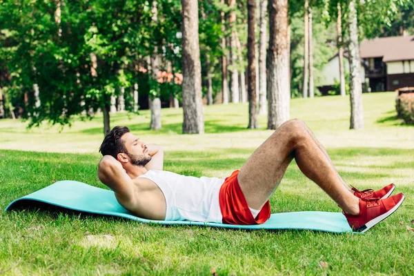 Visão lateral de belo desportista fazendo abdominais no tapete de fitness — Fotografia de Stock