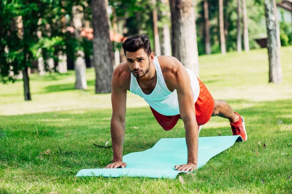 Homem bonito fazendo exercício prancha no tapete de fitness — Fotografia de Stock
