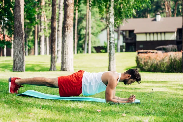 Profile of handsome man doing plank exercise on fitness mat — Stock Photo
