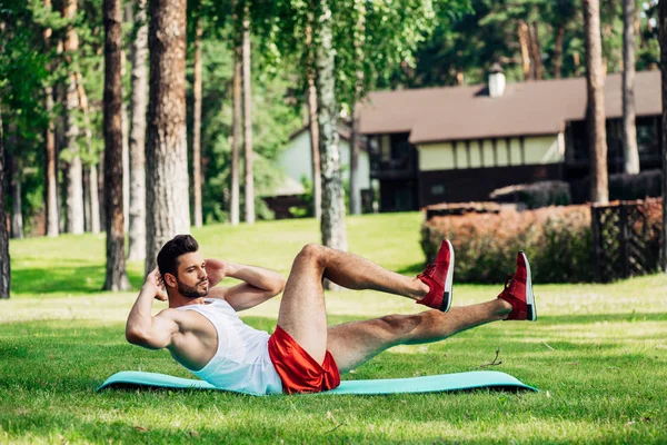 Deportista barbudo haciendo ejercicio en la alfombra de fitness en el parque - foto de stock