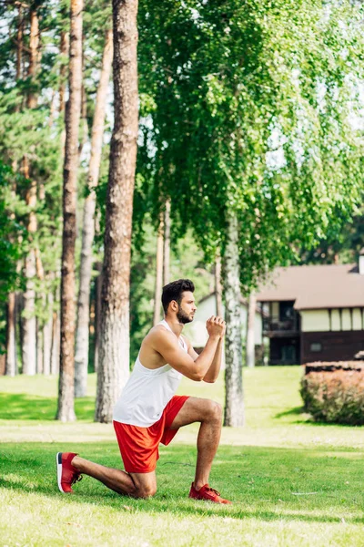 Profile of bearded man training on grass in park — Stock Photo