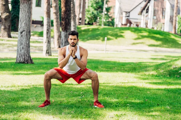 Спортивный бородач тренируется на траве в парке — стоковое фото