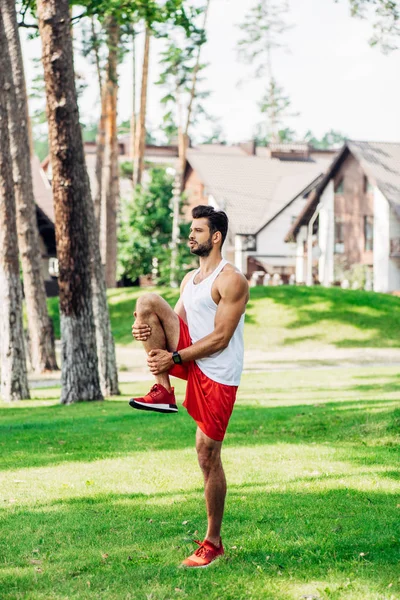 Atletico e bello uomo formazione su erba nel parco — Foto stock