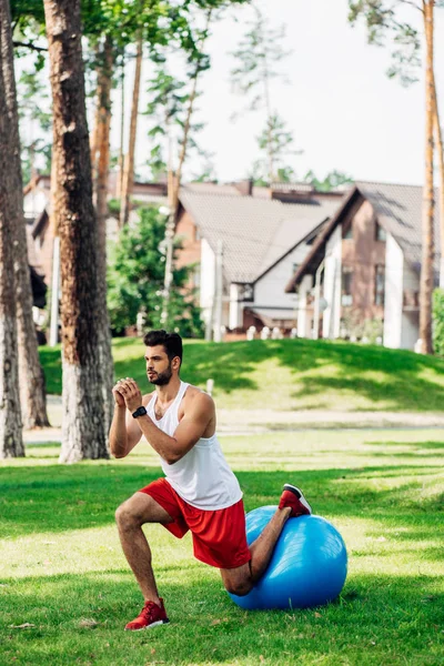 Schöner bärtiger Sportler trainiert auf Fitnessball im Park — Stockfoto